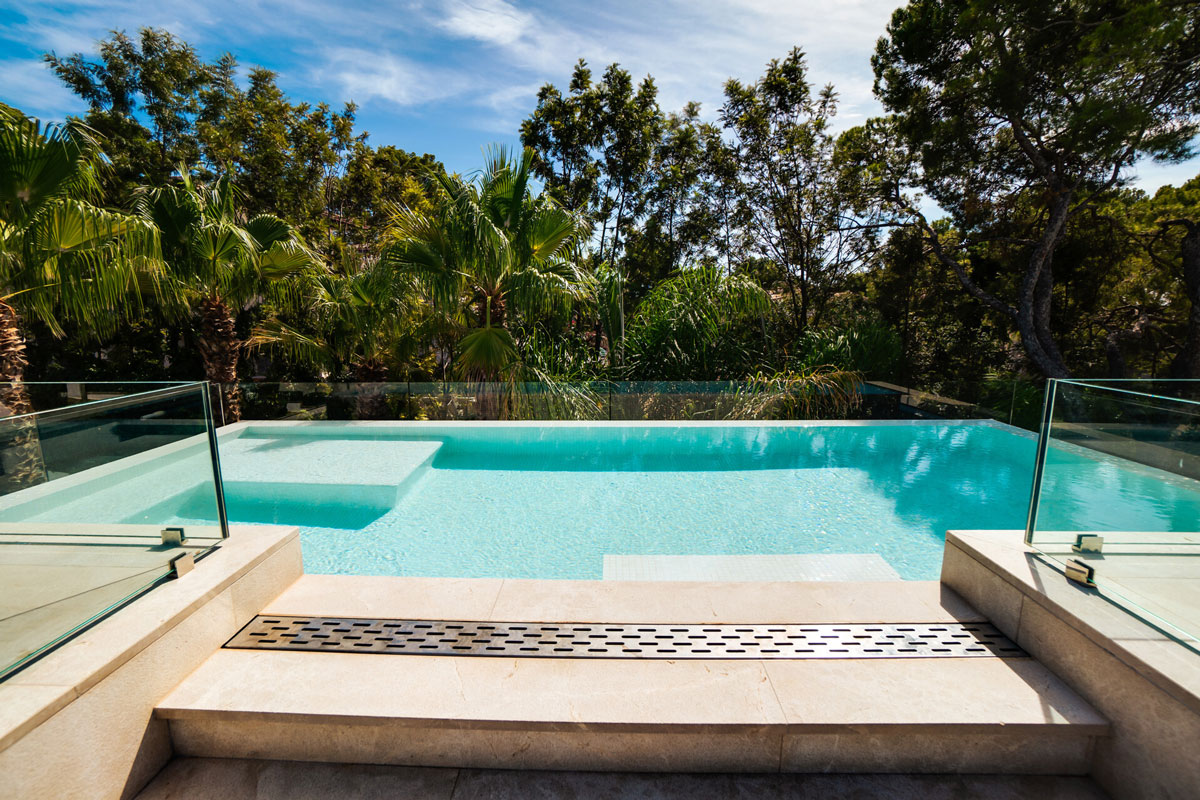  Infinity-Pool mit Glasbrüstung und Ausblick auf tropische Vegetation in exklusiver Villa Mallorca