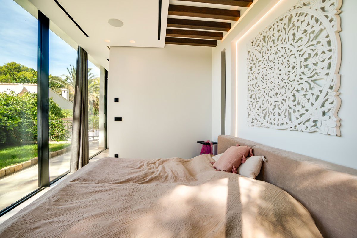 Schlafzimmer mit großem Fenster, Gartenblick und dekorativer Wandkunst in Luxusimmobilie Mallorca